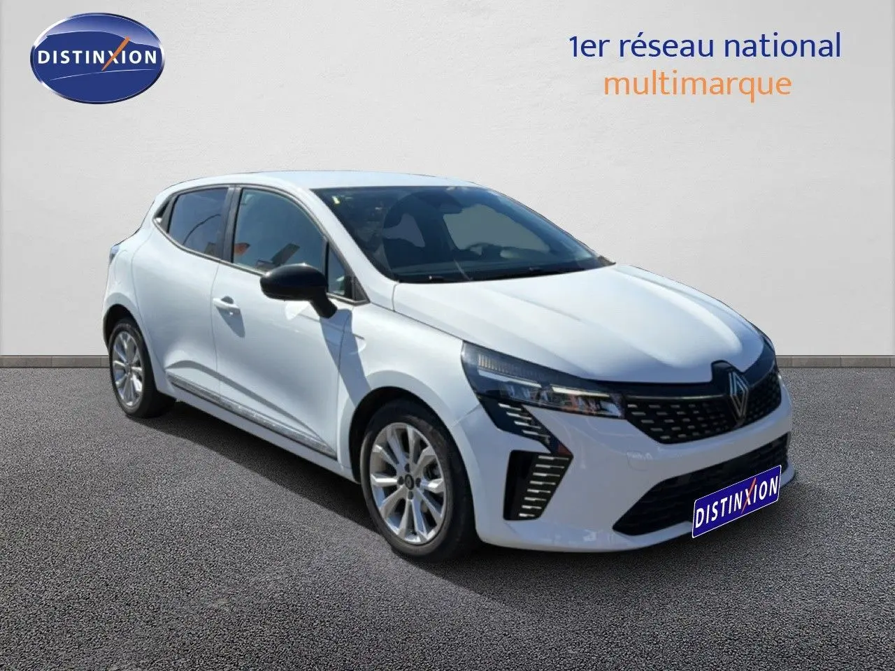 Renault Clio blanche vue 3/4 avant droit, avec calandre moderne et jantes alliage 16 pouces visibles.