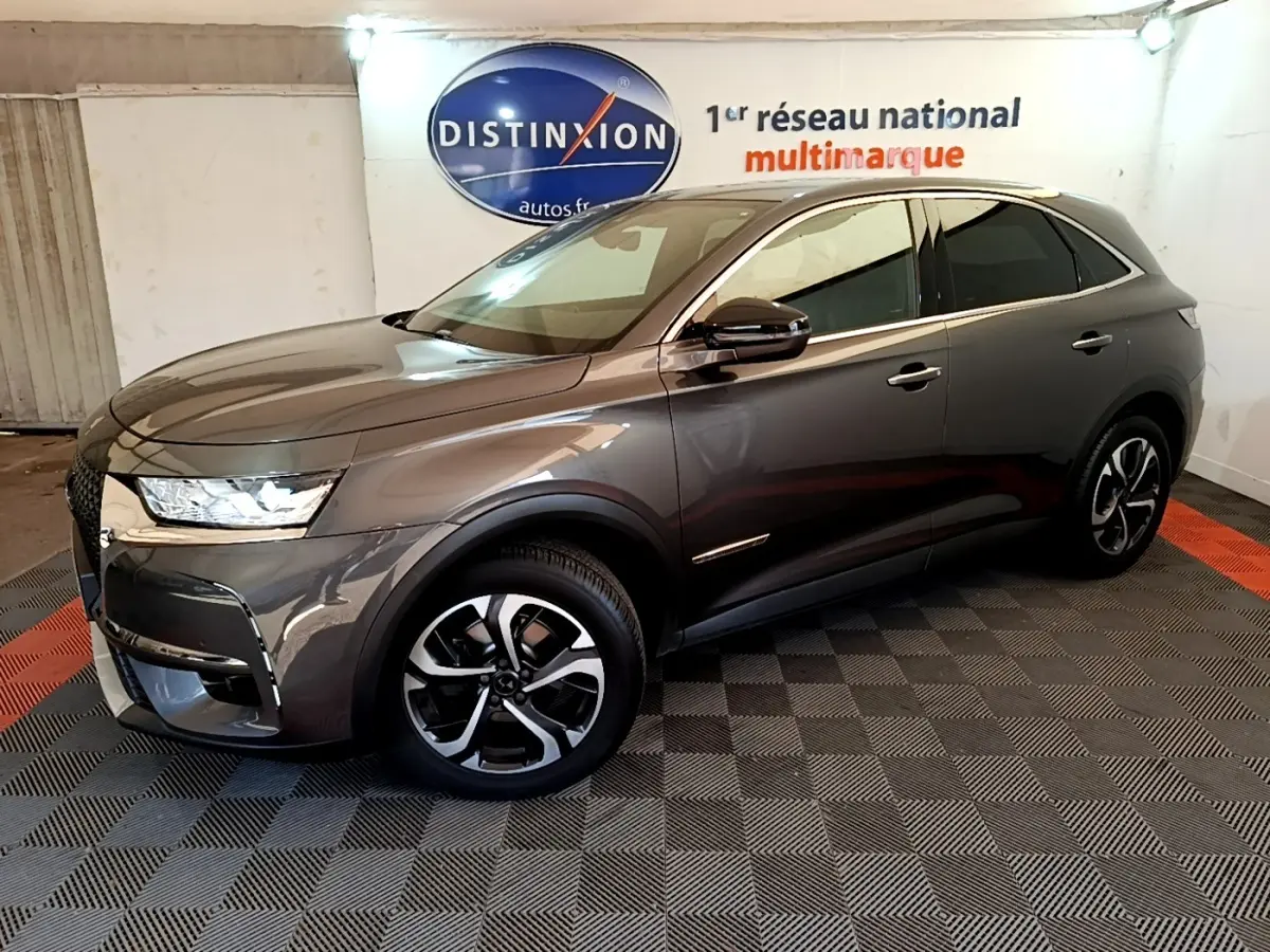 DS7 Crossback gris foncé en 3/4 avant droit, avec jantes alliage et feux LED dans un showroom intérieur.