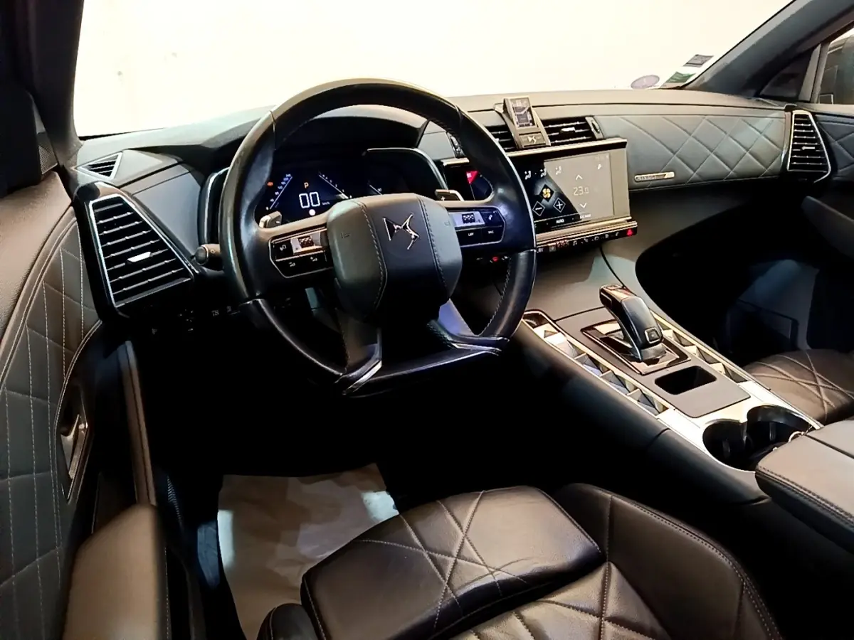 Vue intérieure du poste de conduite du DS7 Crossback avec volant cuir, tableau de bord digital et sellerie cuir matelassée noire.