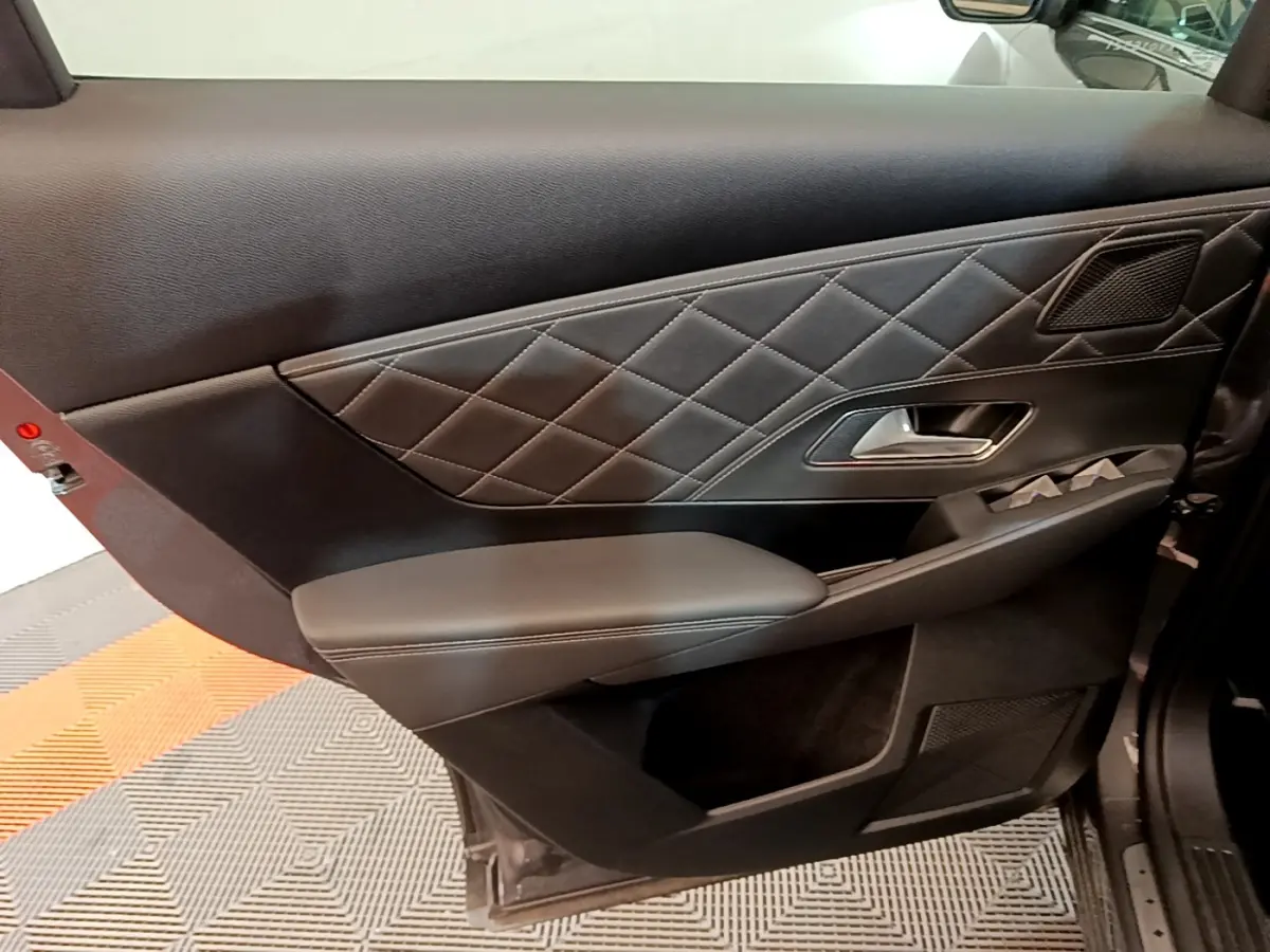 Gros plan sur la porte intérieure côté gauche du DS7 Crossback gris foncé, avec surpiqûres losanges et poignée argentée.