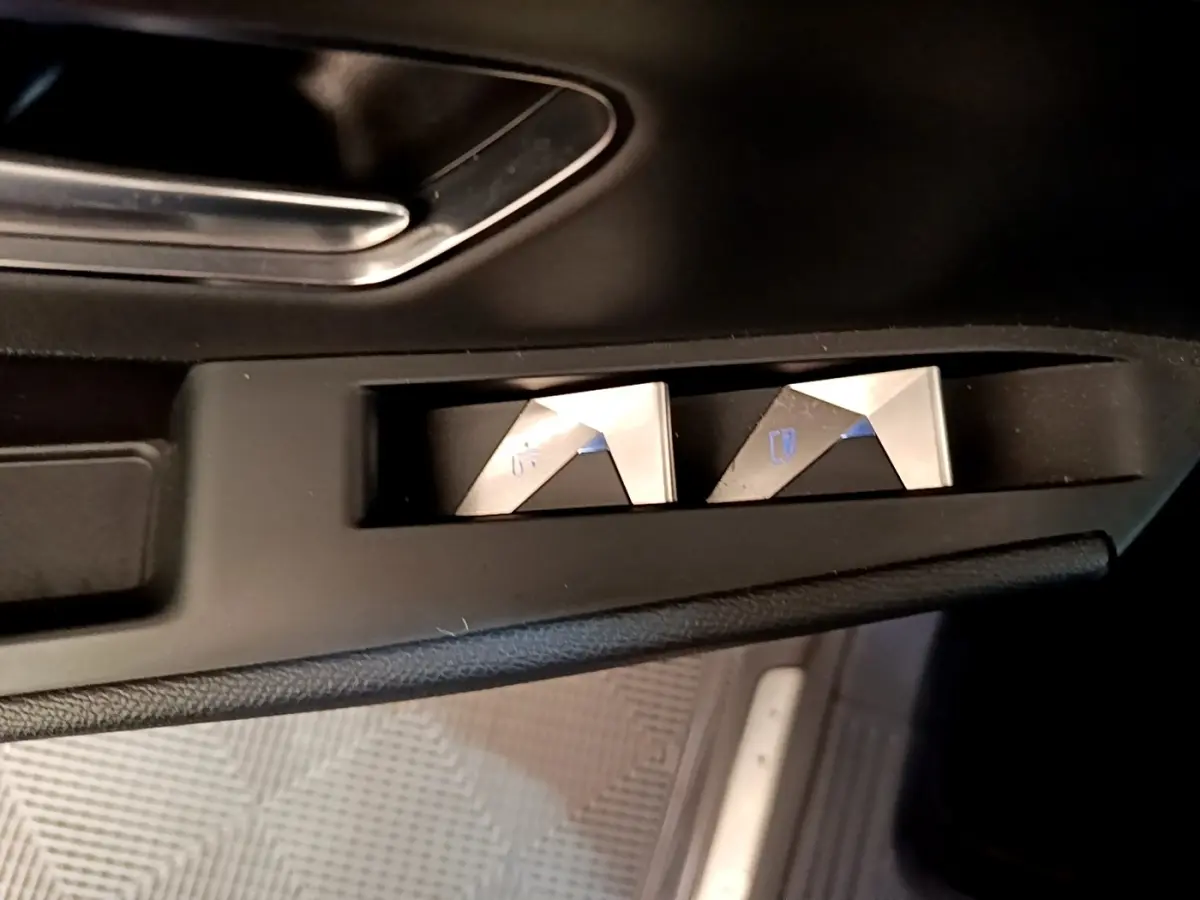 Boutons de commande des vitres électriques en métal brossé sur la portière côté conducteur d’un DS7 Crossback gris foncé.