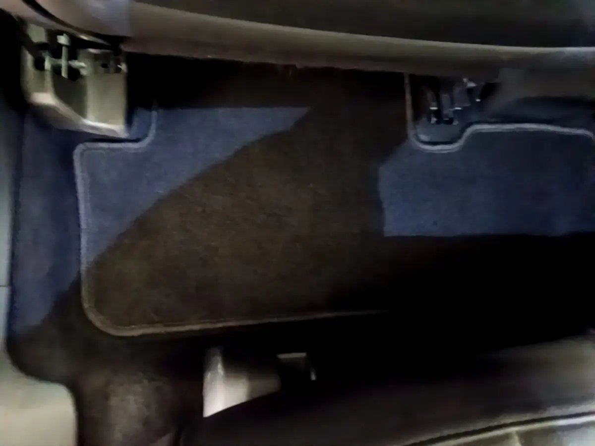 Vue rapprochée du tapis de sol côté conducteur du DS7 Crossback gris foncé, montrant les pédales et le repose-pied.