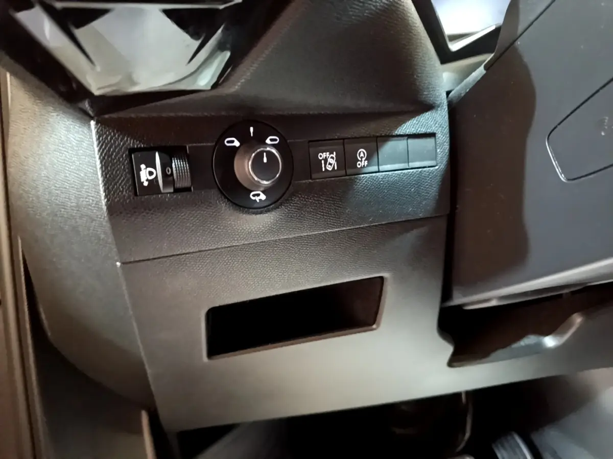 Détail intérieur montrant les commandes d’éclairage et d’assistance au conducteur sur le côté gauche du tableau de bord.