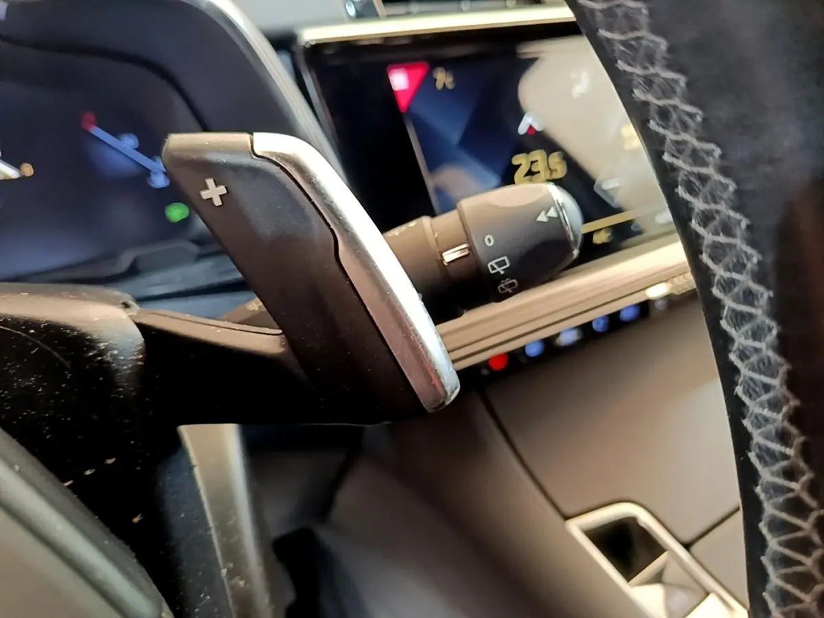 Gros plan sur la palette de changement de vitesse droite et le tableau de bord numérique du DS7 Crossback gris foncé.