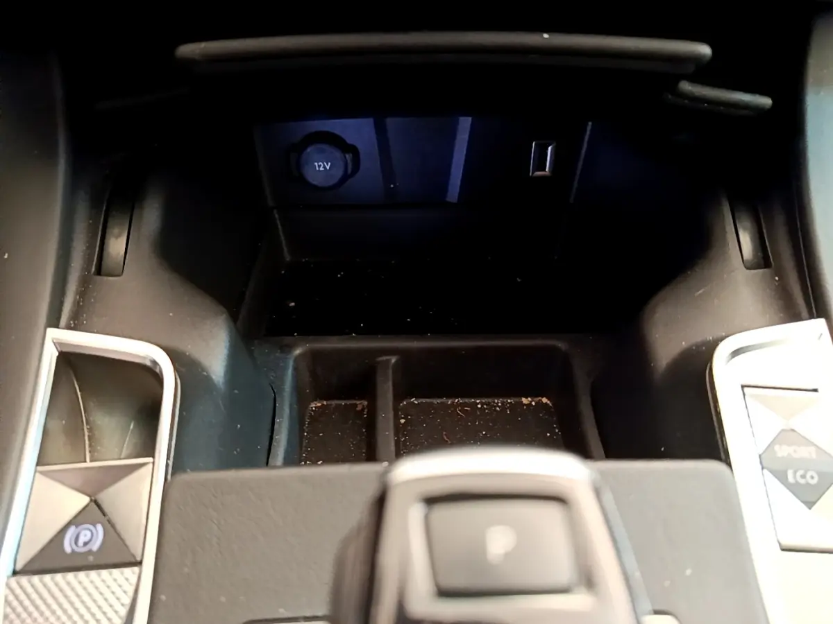 Gros plan sur la console centrale du DS7 Crossback gris foncé, avec bouton frein à main électrique et prises 12V et USB visibles.