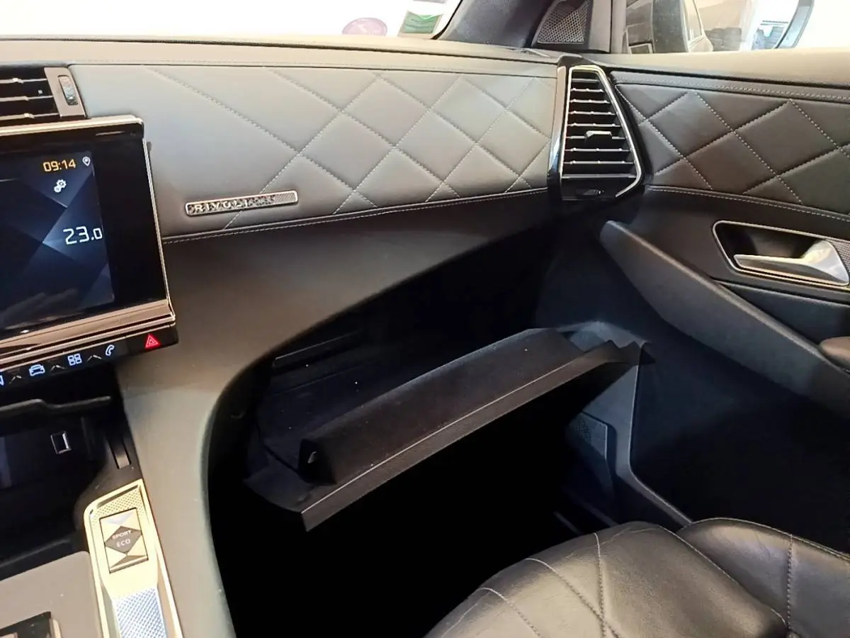 Vue intérieure côté passager du DS7 Crossback gris foncé, montrant la boîte à gants ouverte et la finition cuir matelassée.