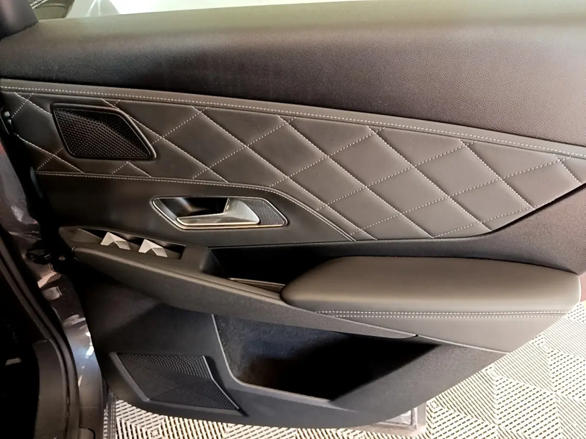 Gros plan sur la porte intérieure côté gauche du DS7 Crossback gris foncé avec surpiqûres et poignée métallique.