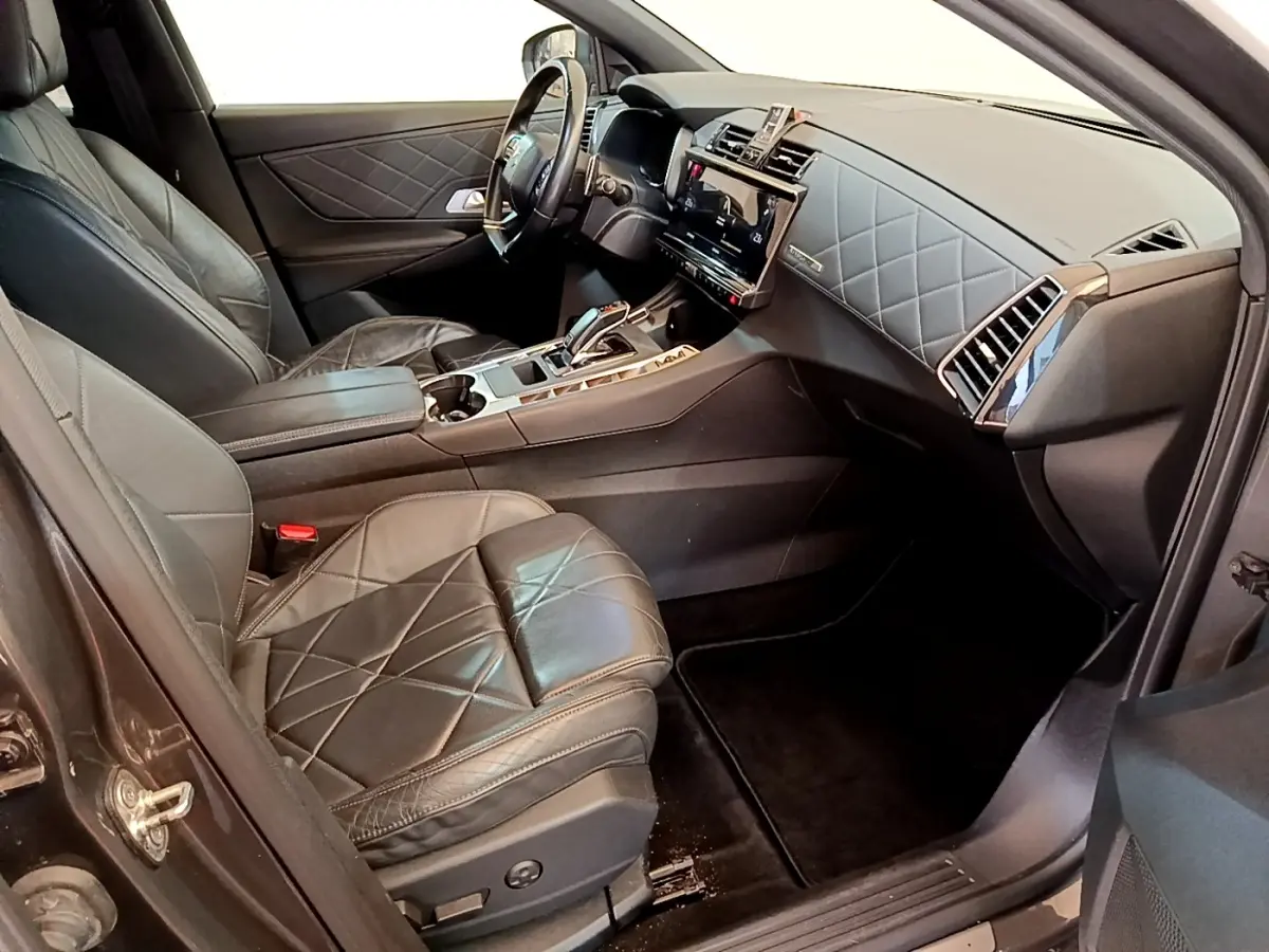 Vue intérieure côté conducteur du DS7 Crossback gris foncé, sièges cuir matelassé et tableau de bord moderne avec écran tactile.