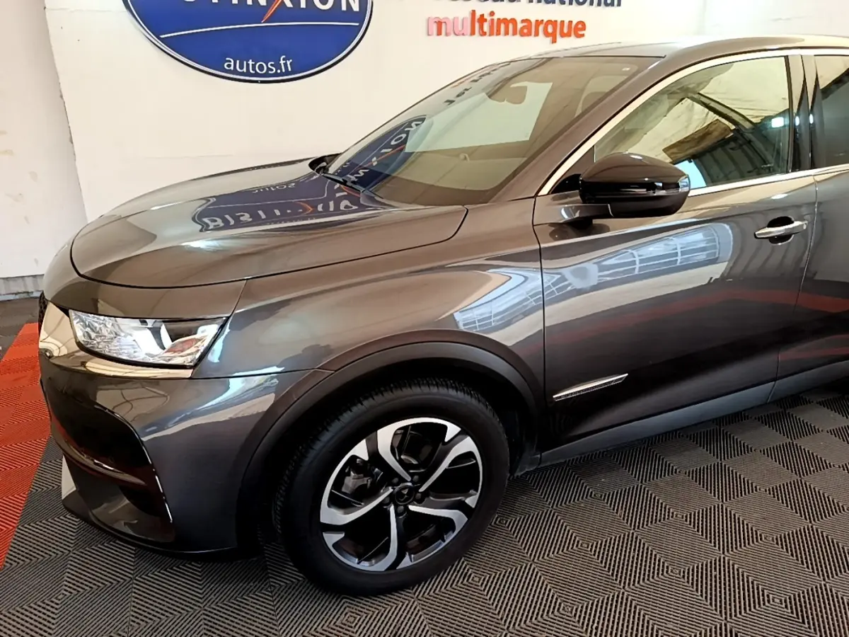 Vue 3/4 avant droit du DS7 Crossback gris foncé, mettant en valeur ses phares LED et jantes alliage bicolores.