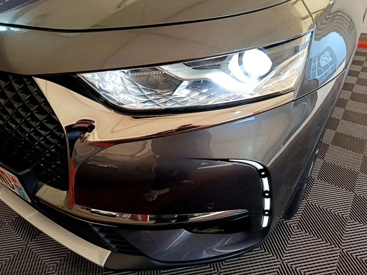 Gros plan sur l'avant droit gris foncé du DS7 Crossback 2019, mettant en valeur le phare LED et la calandre chromée.