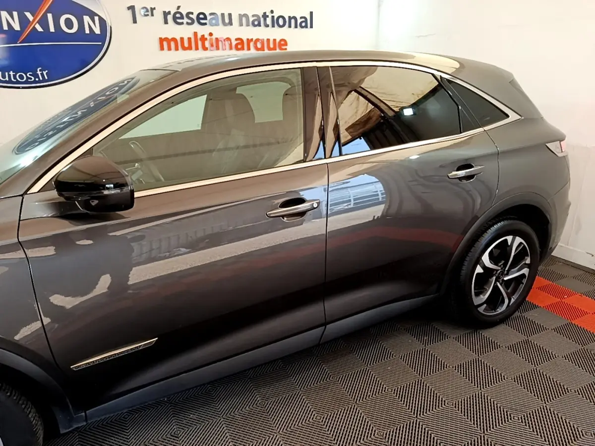 Vue de profil côté gauche du DS7 Crossback gris foncé avec jantes alliage et vitres teintées.