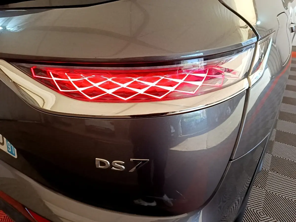 Gros plan sur le feu arrière droit rouge à motif losange du DS7 Crossback gris foncé, avec logo DS7 visible.