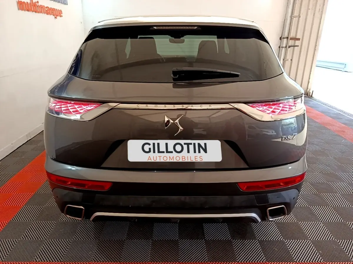 Vue arrière d'un DS7 Crossback gris foncé avec feux LED et double sortie d'échappement carrée, en intérieur showroom.
