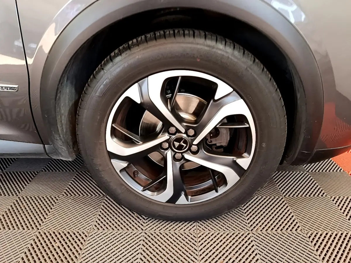 Gros plan sur la roue avant gauche du DS7 Crossback gris foncé, mettant en valeur la jante alliage à cinq branches doubles.