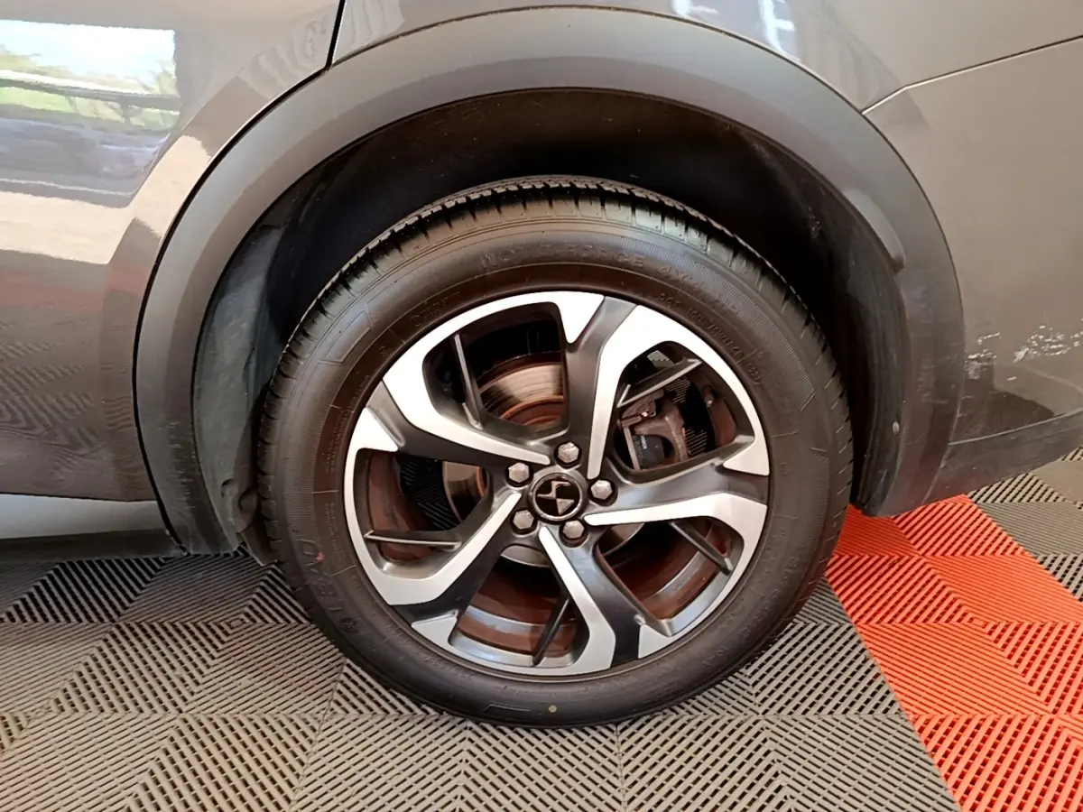 Gros plan sur la roue avant droite d’un DS7 Crossback gris foncé, mettant en valeur la jante alliage bicolore.