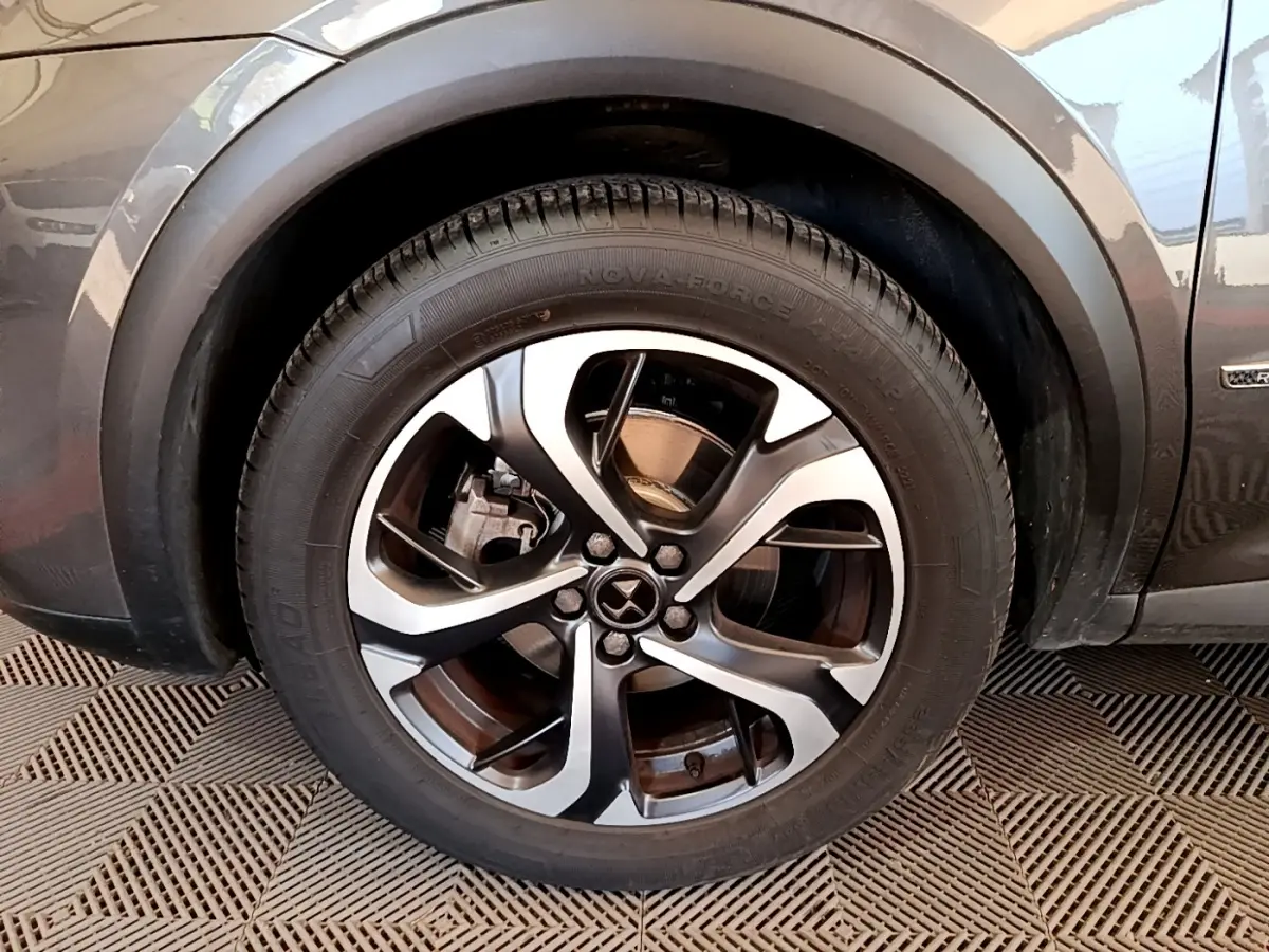 Gros plan sur la roue avant gauche et la jante en alliage du DS7 Crossback gris foncé, avec logo DS visible.