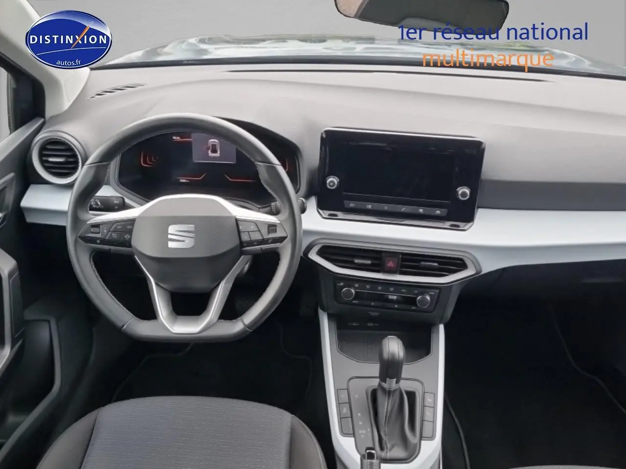 Vue intérieure frontale du tableau de bord et volant cuir méplat de la SEAT Arona 2025 gris magnétique avec écran tactile et console centrale.