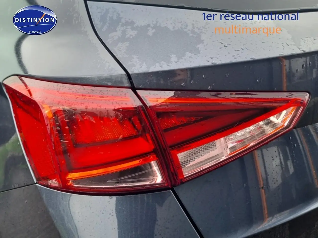 Gros plan sur le feu arrière droit rouge du SEAT Arona gris magnétique 2025 sous la pluie.