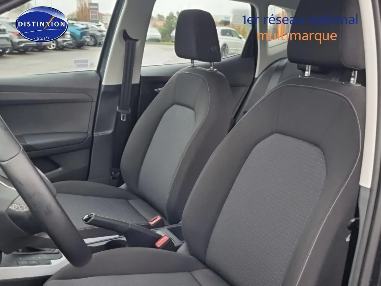 Vue intérieure côté avant droit du SEAT Arona 2025 avec sièges tissu gris Como et volant multifonction cuir méplat.