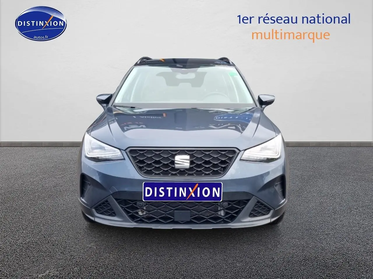 Vue frontale d'un SEAT Arona gris magnétique avec calandre noire et projecteurs full LED allumés.