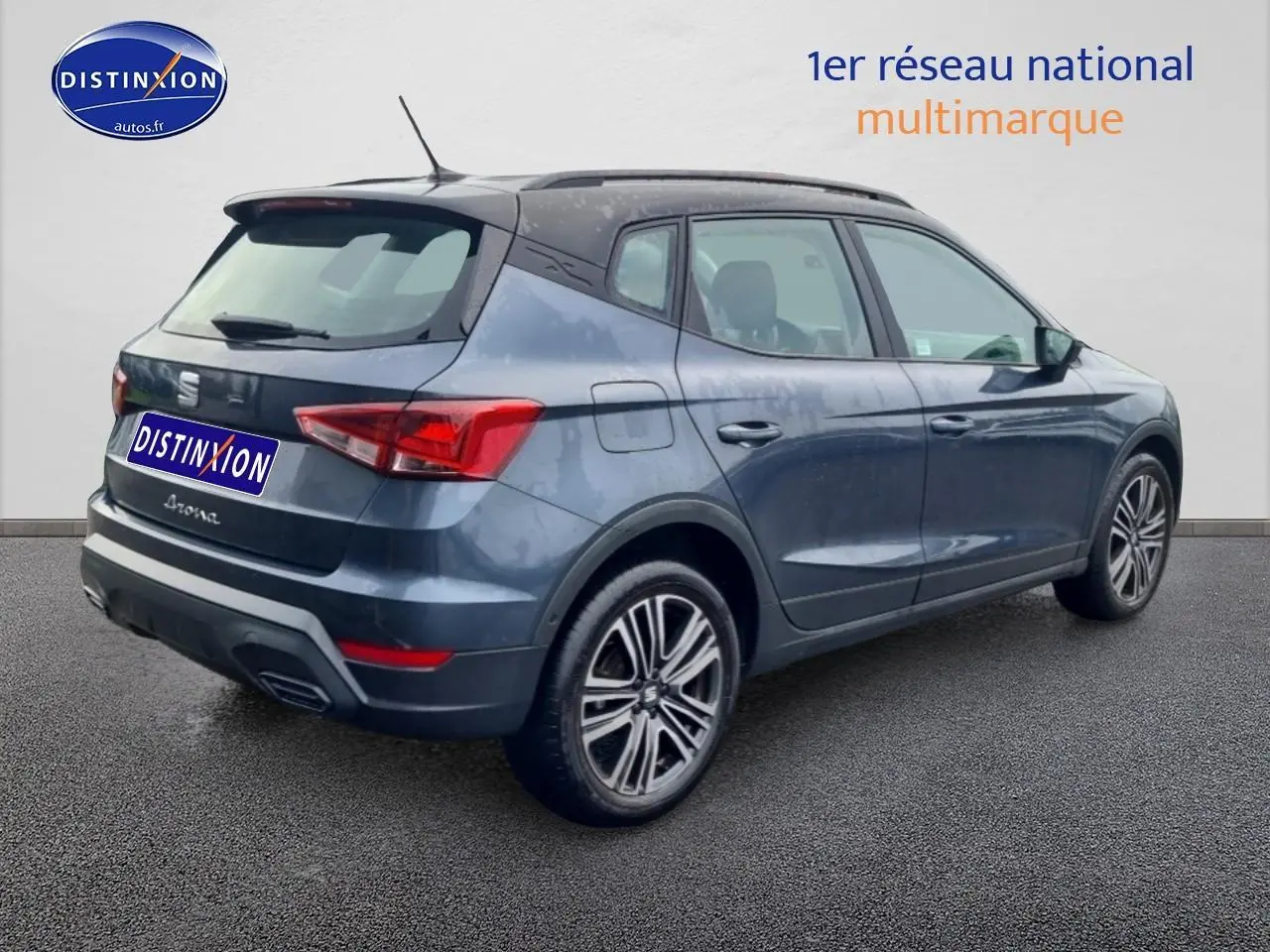 Vue 3/4 arrière droite d'un SEAT Arona gris magnétique avec jantes 17 pouces et barres de toit noires.