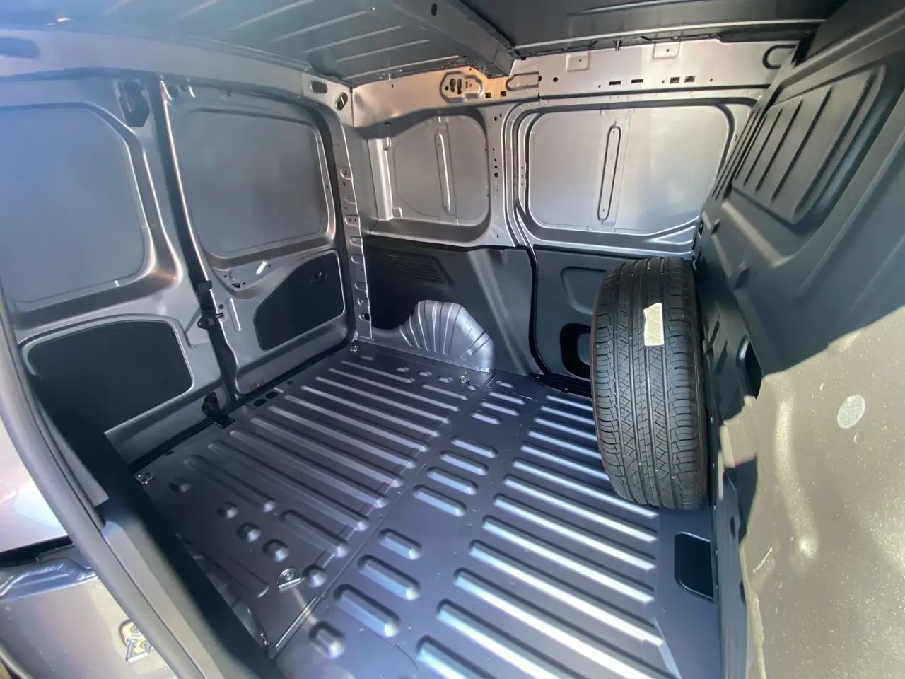 Intérieur du fourgon Peugeot Partner Dangel 4x4 gris Artense, vue de la zone de chargement avec roue de secours.