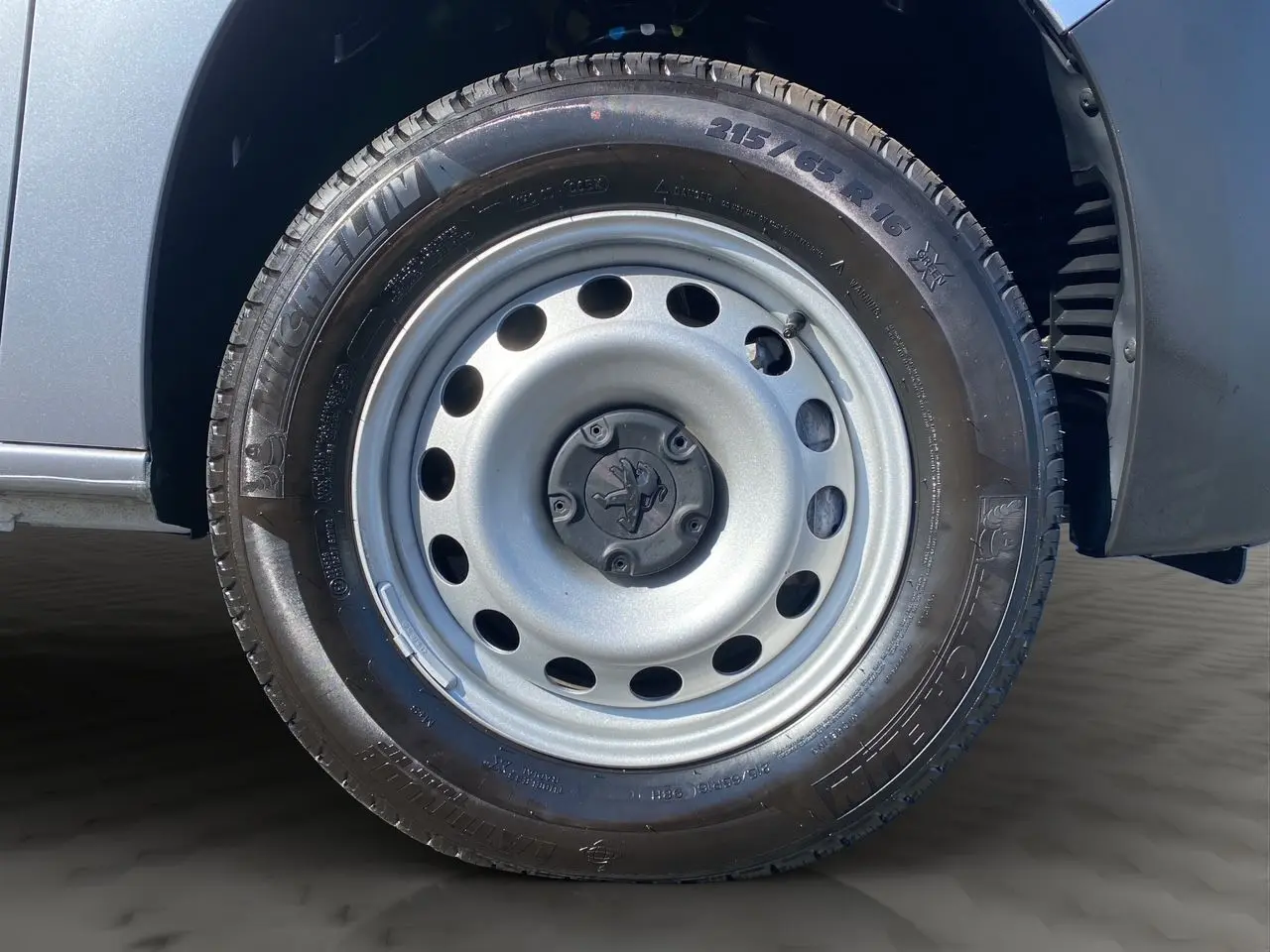 Gros plan sur la roue avant droite en jante tôle grise du Peugeot Partner Fourgon Dangel 4x4 gris Artense.
