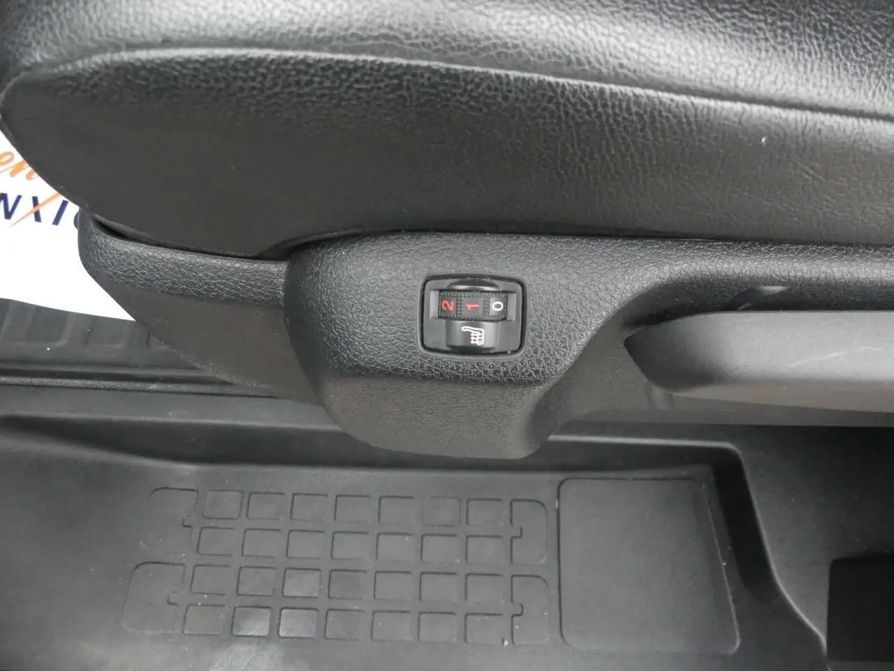 Gros plan sur le bouton de siège chauffant noir sous le siège avant du Peugeot Expert Fourgon blanc.