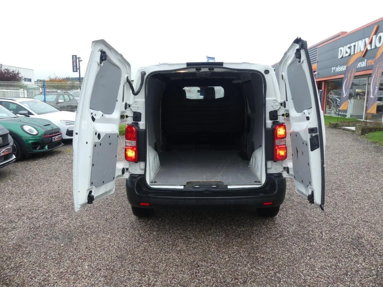 Vue arrière du Peugeot Expert Fourgon blanc 2019 avec portes arrière ouvertes et espace de chargement vide visible.