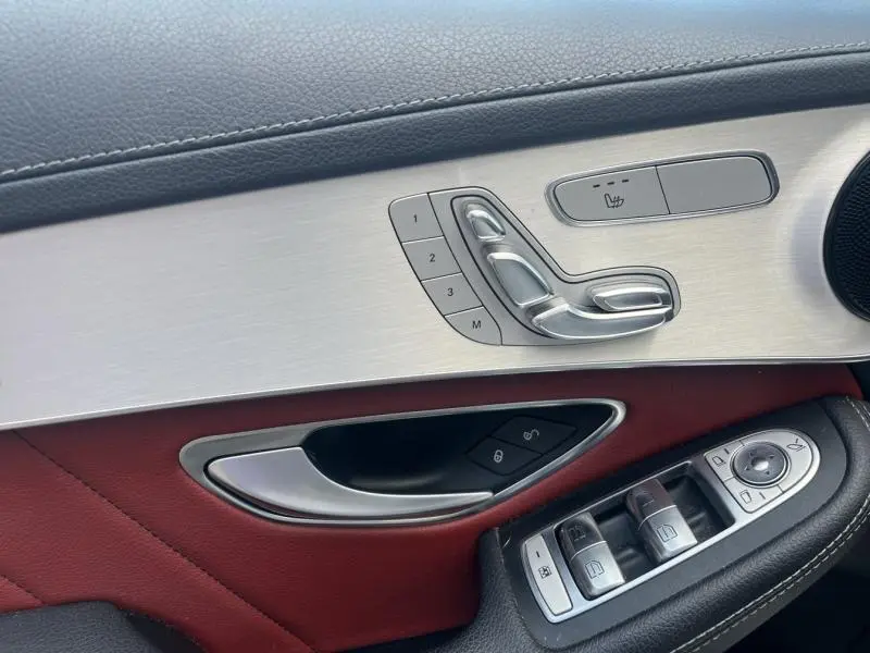 Gros plan sur la porte avant gauche du Mercedes GLC Coupé blanc diamant, cuir rouge/noir et commandes sièges mémoire.