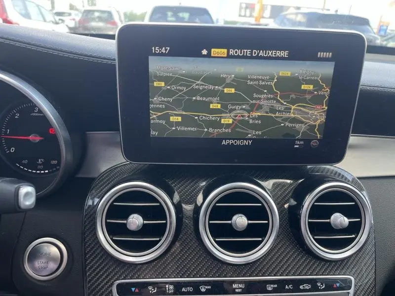 Vue intérieure du tableau de bord du Mercedes GLC Coupé blanc diamant, mettant en valeur l'écran GPS et les aérateurs ronds chromés.
