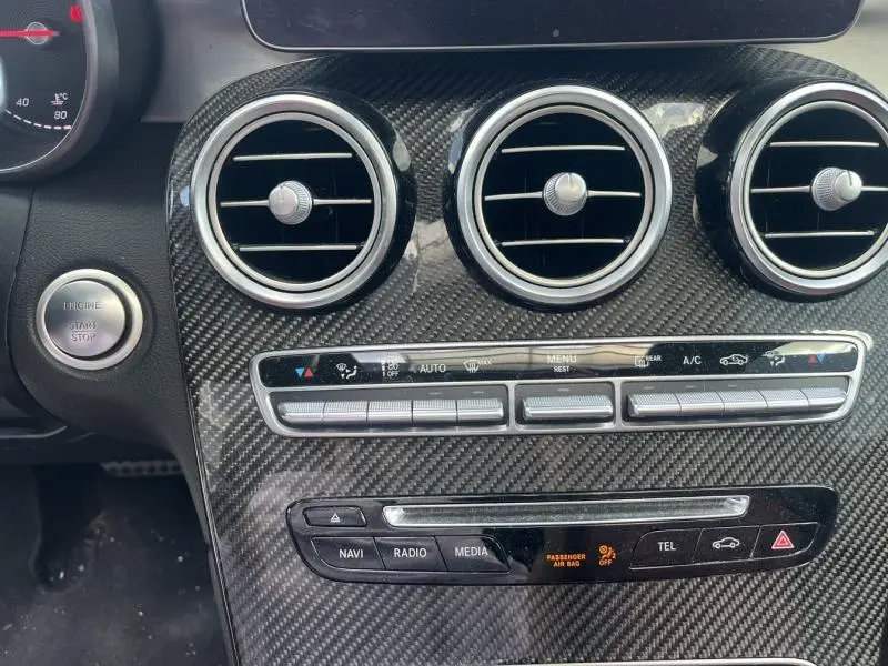 Vue rapprochée du tableau de bord en carbone du Mercedes GLC Coupé blanc diamant, avec commandes clim et multimédia visibles.