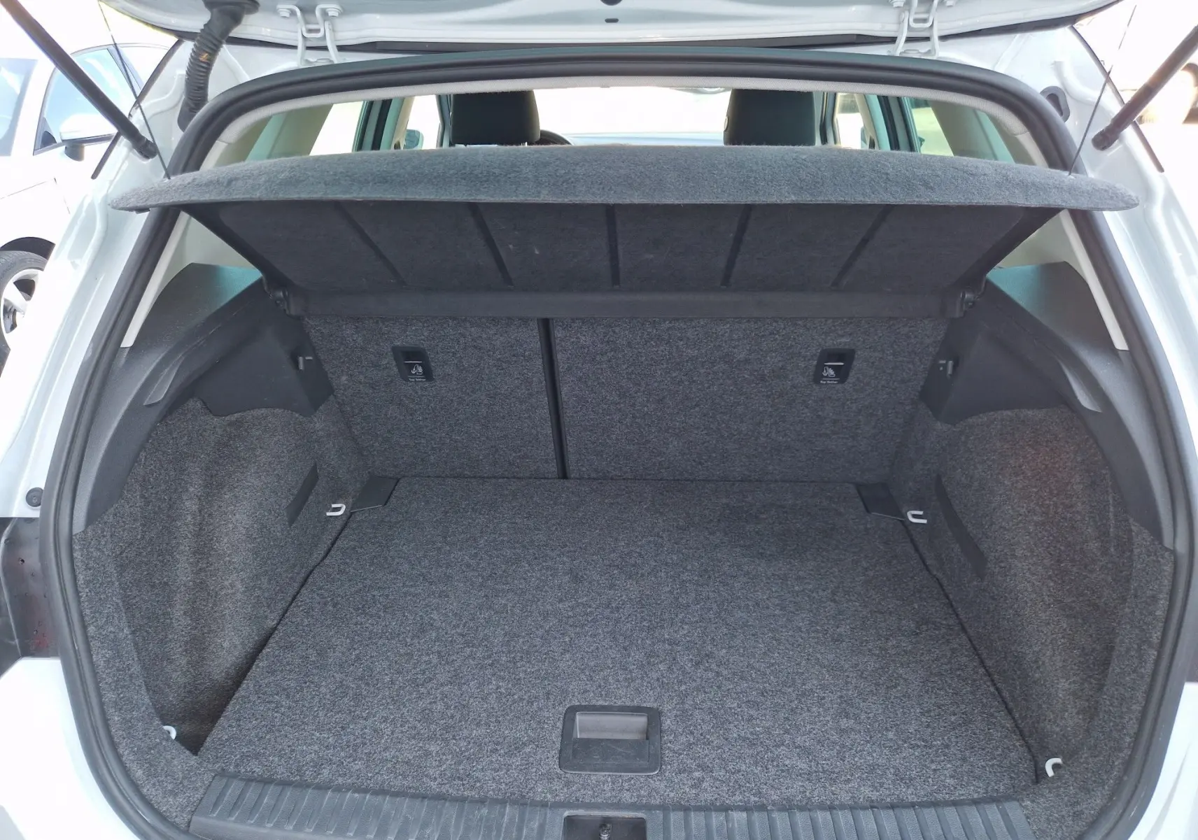 Coffre ouvert vu de l’arrière d’un SEAT Arona blanc alpin métal avec toit noir, montrant l’espace de chargement vide et la tablette arrière relevée.