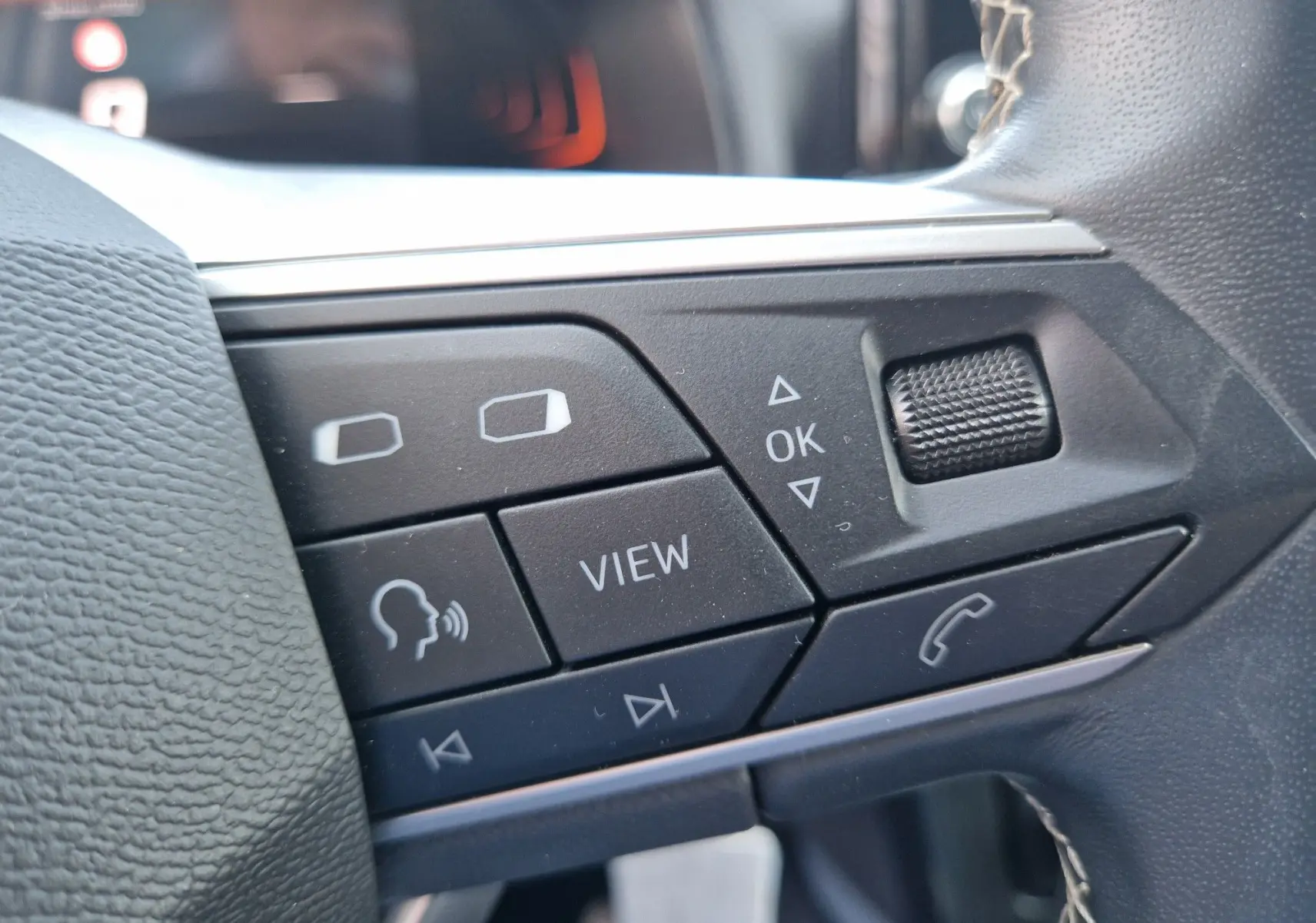 Gros plan sur les commandes noires au volant du SEAT Arona 2025, avec boutons multifonctions et molette crantée.