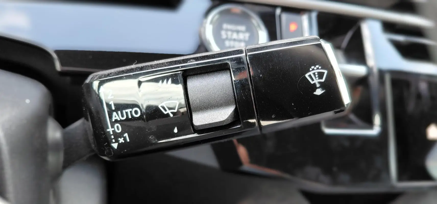 Gros plan sur la commande des essuie-glaces du Peugeot 3008 Hybrid 136 e-DCS6 Allure, intérieur noir brillant.