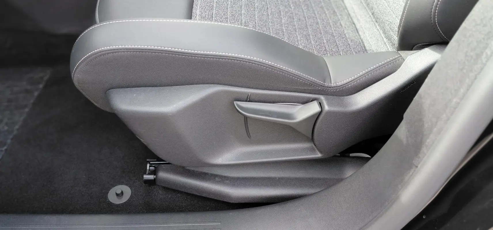 Détail de la commande de réglage manuel du siège avant droit du Peugeot 3008 Hybrid 136 e-DCS6 Allure noir 2025.