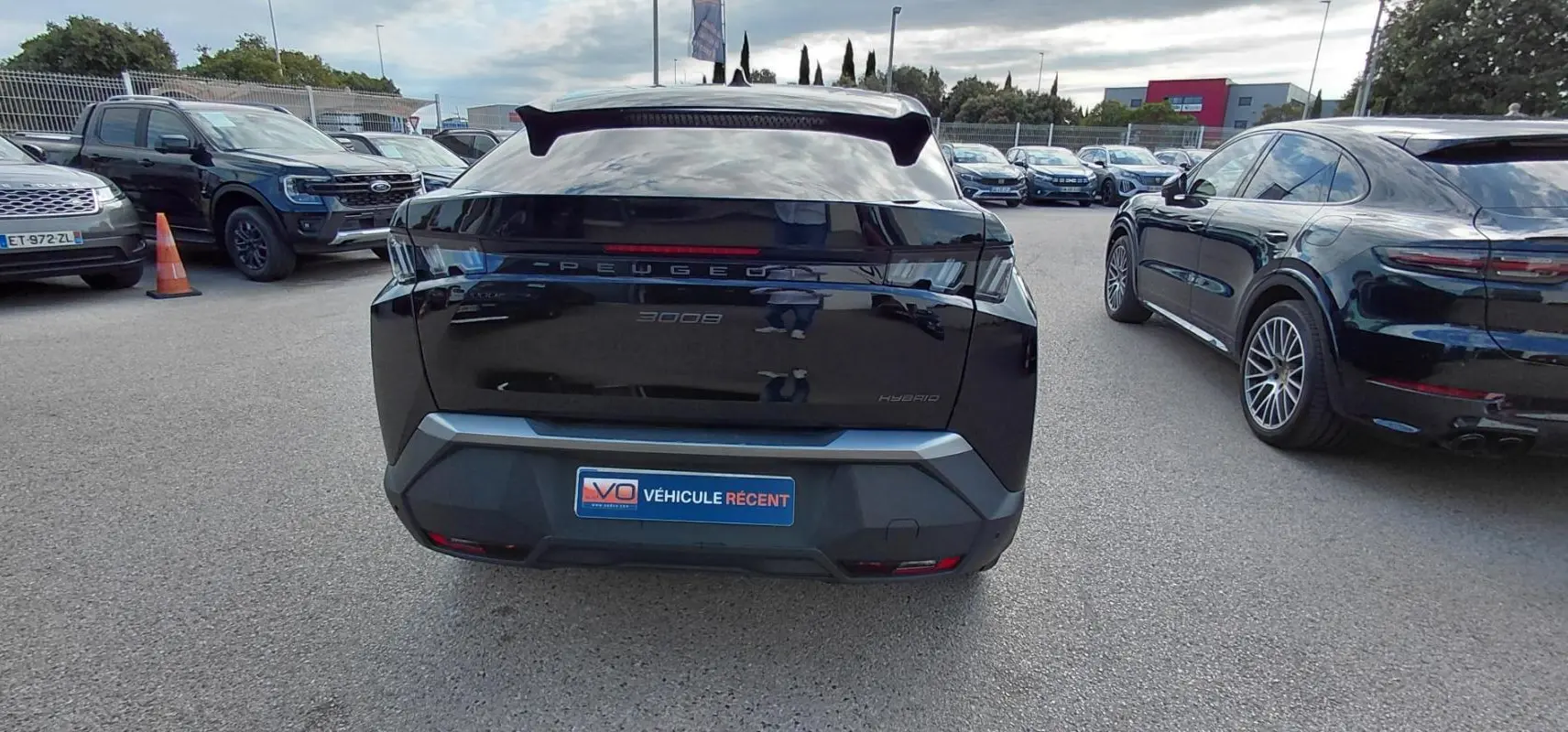 Vue arrière d’un Peugeot 3008 Hybrid noir 2025 avec jantes alliage 19 pouces sur parking extérieur.