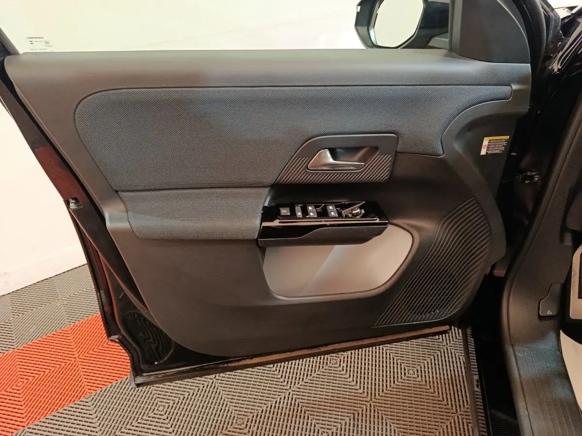 Vue intérieure de la porte avant gauche noire du Citroën C5 Hybride 2026 avec commandes électriques et finition texturée.
