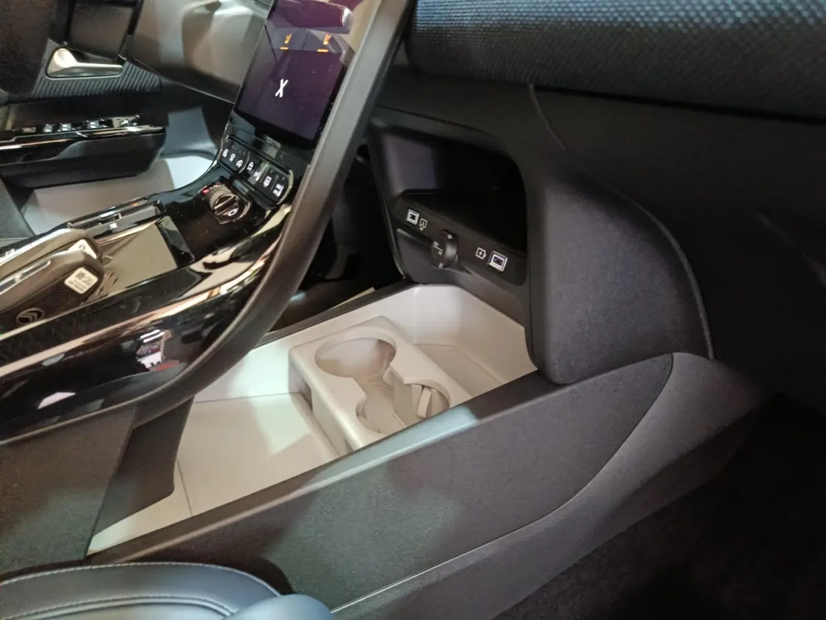 Détail intérieur de la console centrale noire du Citroën C5 Hybride 2026 avec porte-gobelets et commandes.