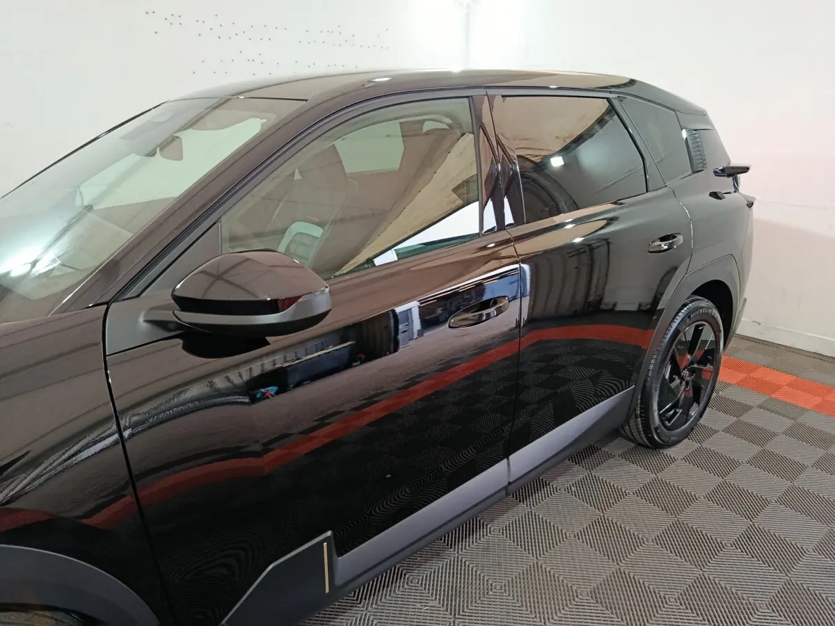 Vue latérale droite d'une Citroën C5 Hybride noire 2026 avec jantes noires et détails chromés sur porte.