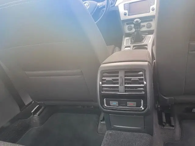 Vue arrière de l'habitacle d'une Volkswagen Passat reflet d'argent 2015, montrant les aérateurs et la boîte manuelle.