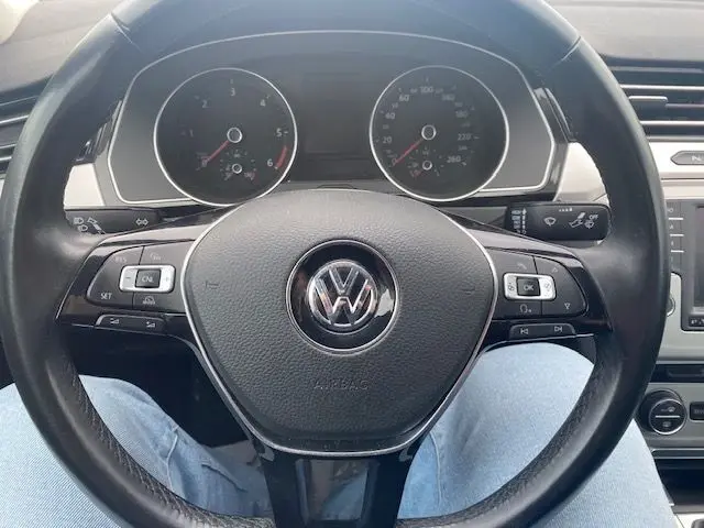 Vue rapprochée du volant noir de la Volkswagen Passat 2015, avec commandes intégrées et tableau de bord visible.