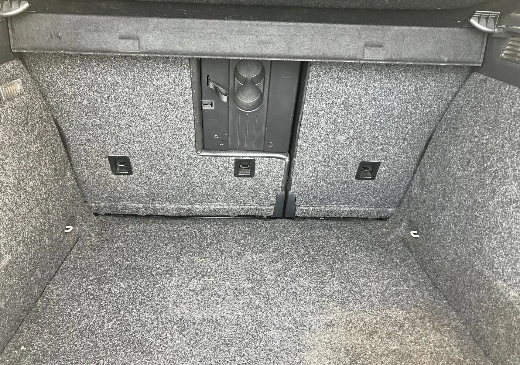 Vue intérieure du coffre gris d'un Volkswagen Tiguan 2013, montrant le revêtement et une trappe centrale.