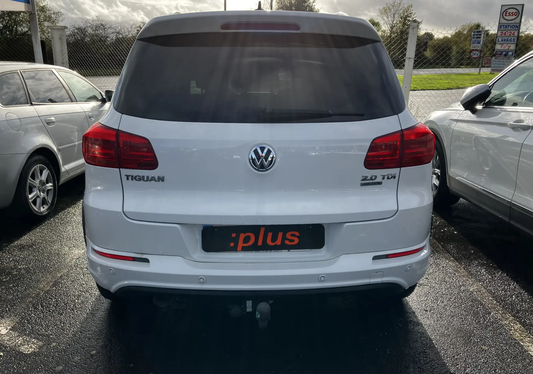 Vue arrière d'un Volkswagen Tiguan blanc 2.0 TDI avec logo et badges visibles sur un parking extérieur.