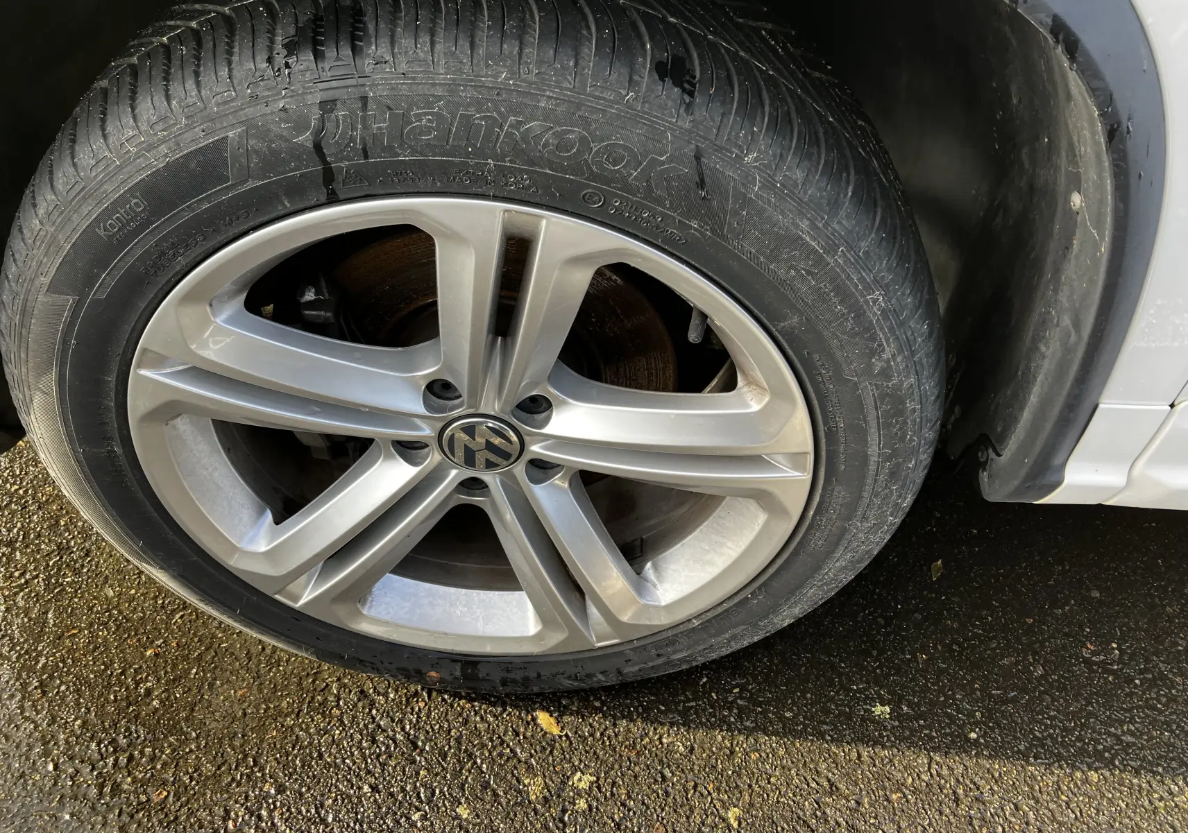 Gros plan sur la roue avant gauche du Volkswagen Tiguan blanc de 2013 avec jante alliage et pneu Hankook.