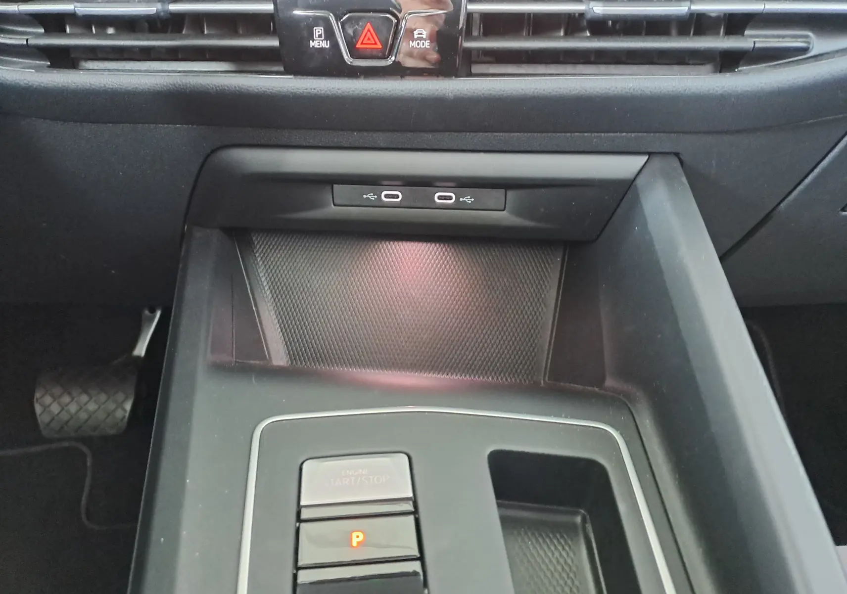 Gros plan sur la console centrale noire de la Volkswagen Golf VIII hybride, montrant les boutons start/stop et parking.