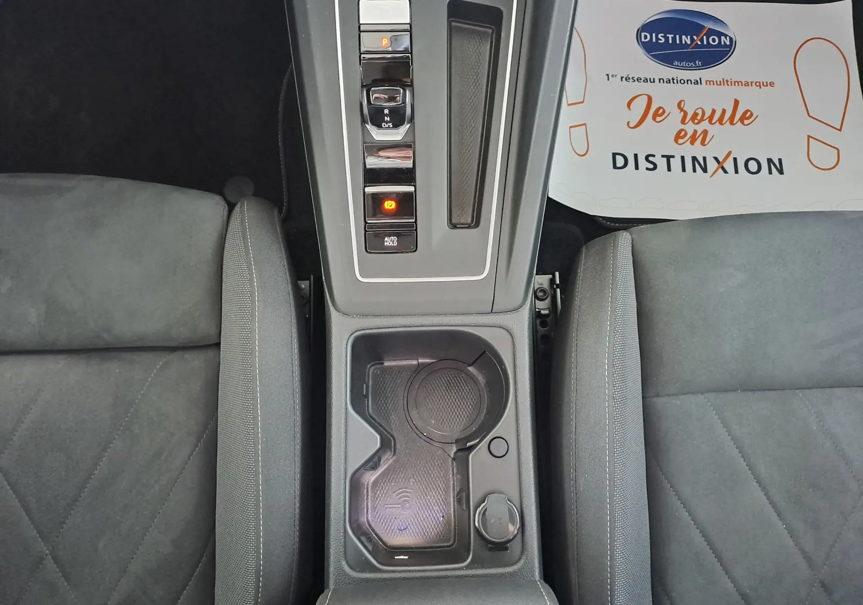 Vue plongeante sur la console centrale grise de la Volkswagen Golf VIII hybride, avec sièges tissu gris et espace porte-gobelets.