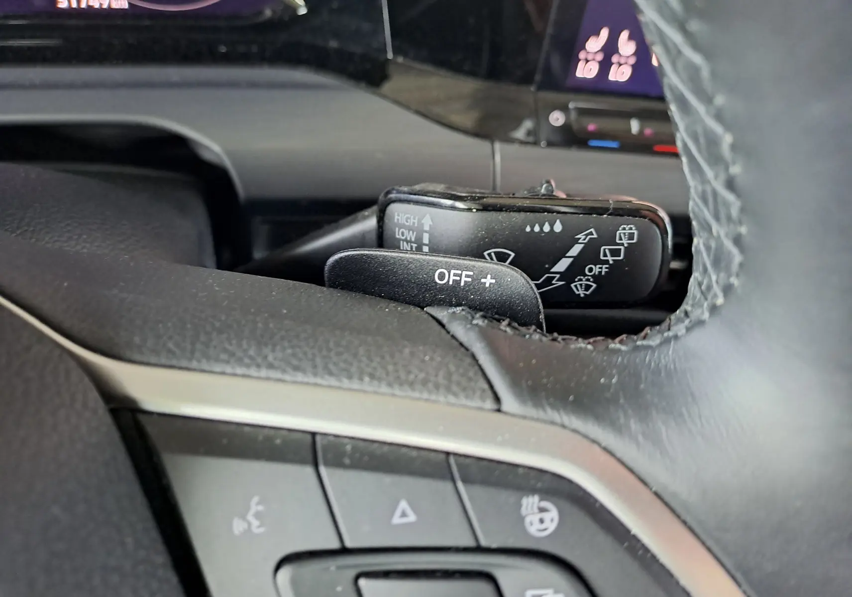 Vue rapprochée du commodo d'essuie-glace et du volant en cuir noir de la Volkswagen Golf VIII gris dauphin, intérieur moderne.