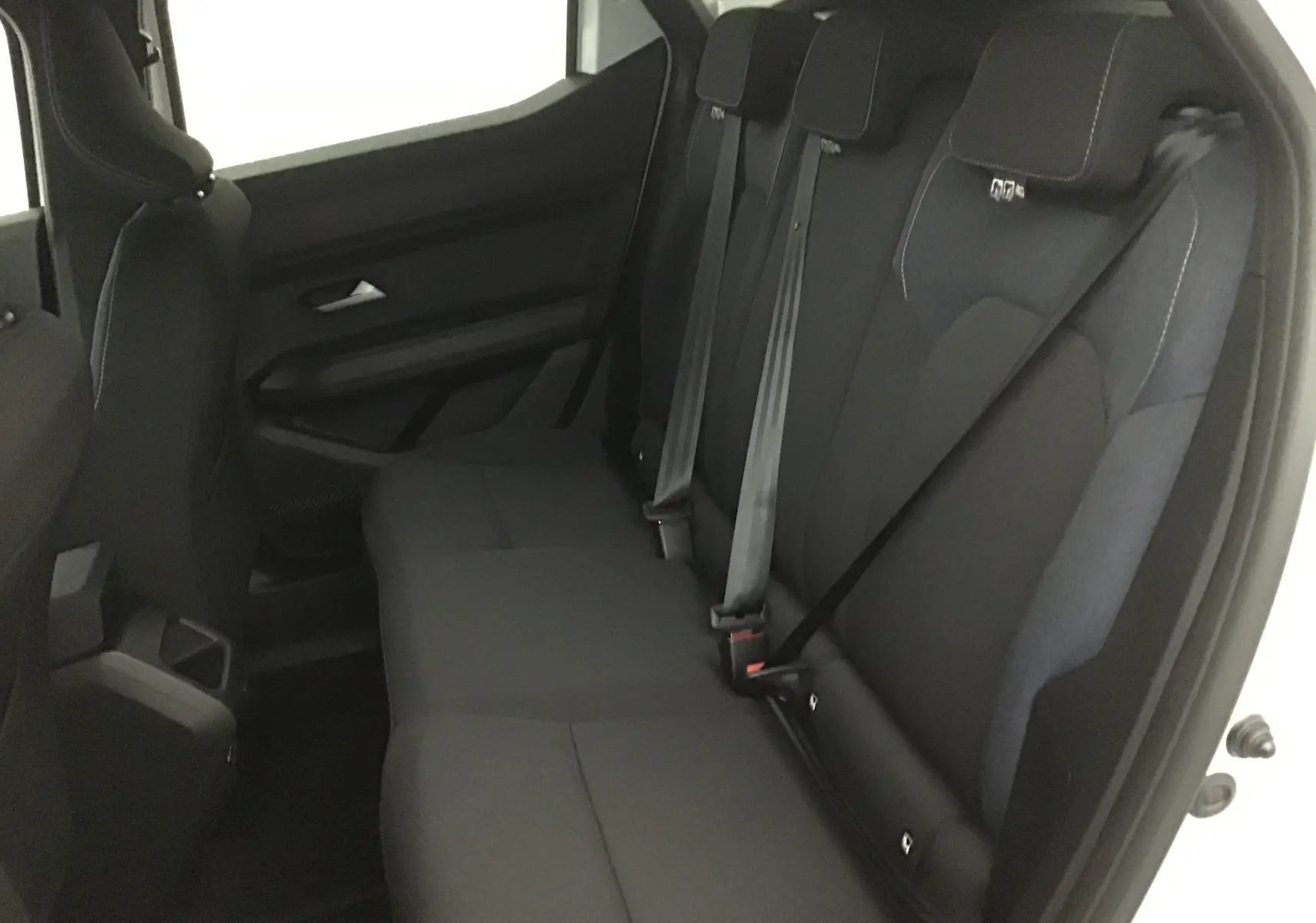 Vue intérieure du siège arrière droit du Dacia Duster blanc glacier 2025 avec ceintures de sécurité visibles.