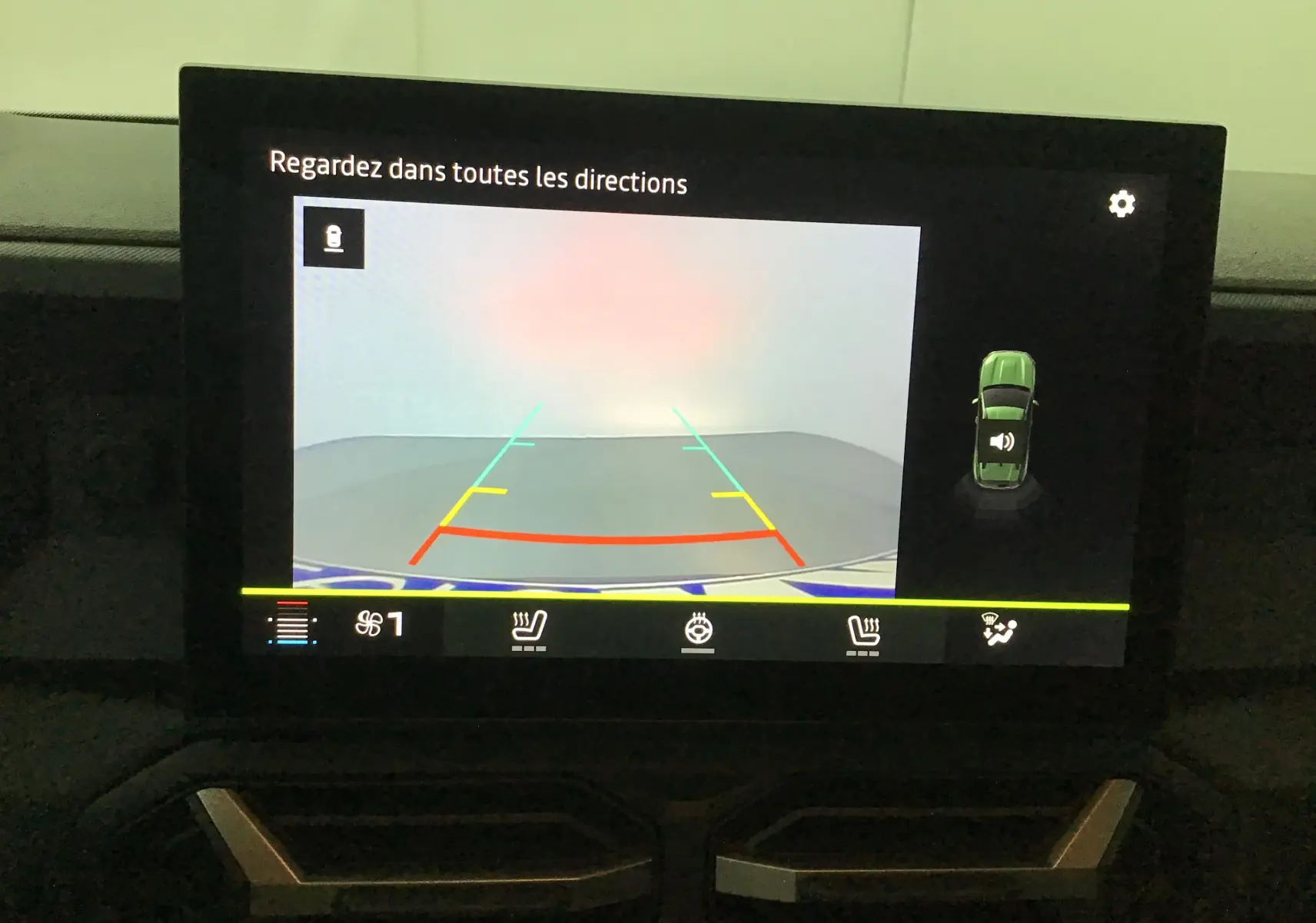 Écran intérieur du Dacia Duster 2025 montrant la caméra de recul avec lignes de guidage colorées et affichage des commandes de sièges chauffants.